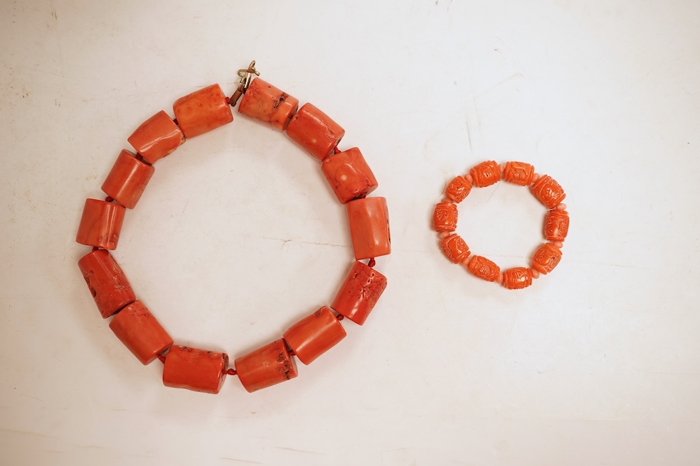 Two coral bead necklaces, one composed of large cylindrical coral beads, approximately 2.5-3.5cm each, total length 49cm; and a bracelet composed of carved coral beads spaced by smaller pink coral beads, on an elasticate